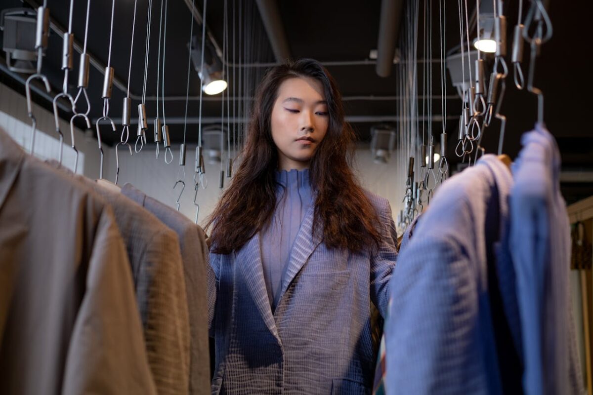 Offres A stylish young woman browsing clothing options in a chic boutique.